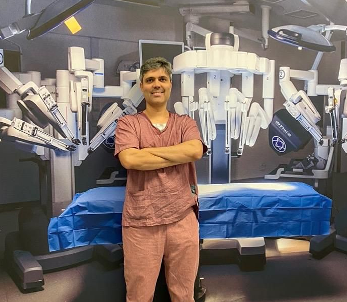 Dr. Daniel Porto ao lado da plataforma robótica Da Vinci em centro cirúrgico
